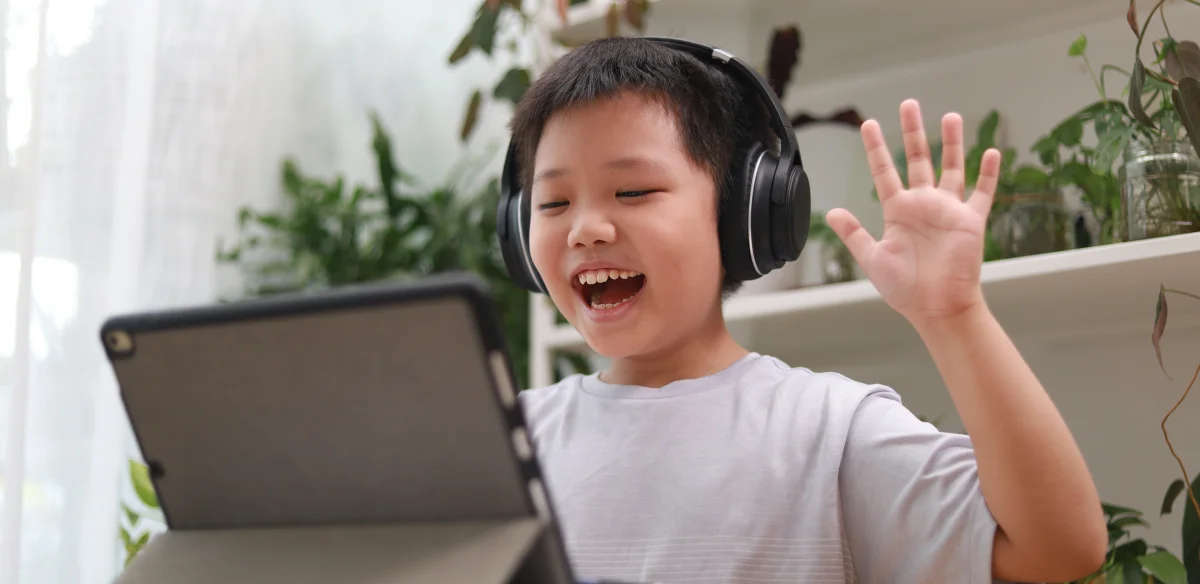 Elementary student wearing a black pair of headphones while attending to an online class