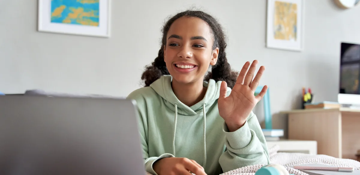 High school student wearing a green hoodie while attending to an online class at home